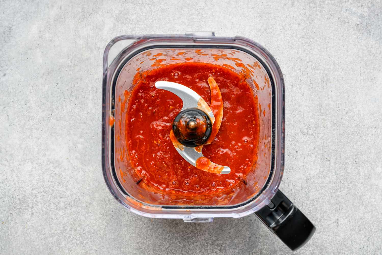 A blender with a sauce made from blended chiles de arbol, guallijo chiles, Roma tomatoes, and garlic