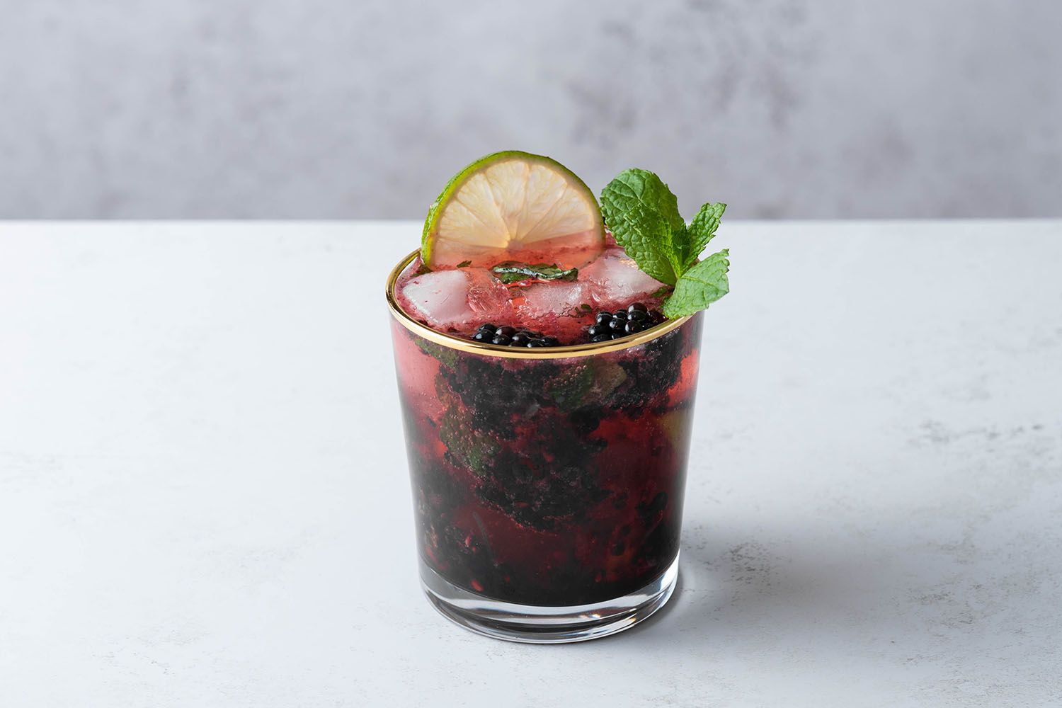 Blackberry Mojito garnished with a lime wedge and mint 