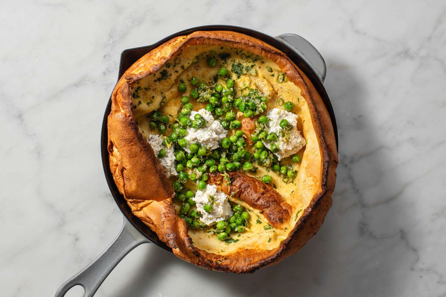 A Dutch Baby topped with Boursin cheese and cooked peas