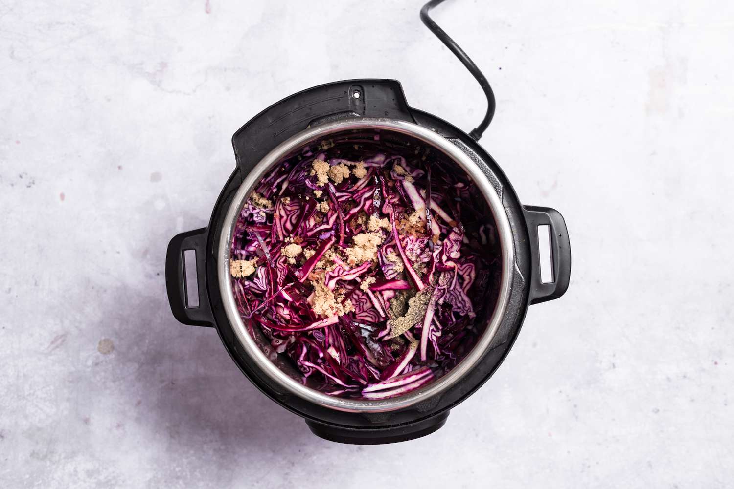 Cabbage, vinegar, brown sugar, salt, and pepper added to the onion mixture in an Instant Pot
