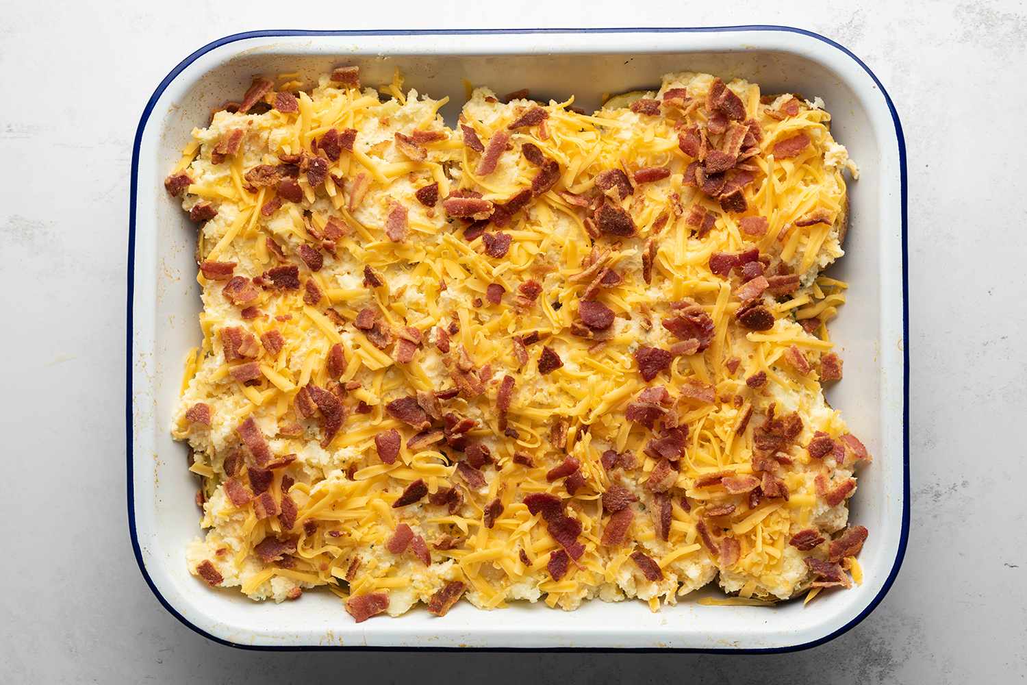 Potatoes in a baking dish, topped with cheese and bacon 