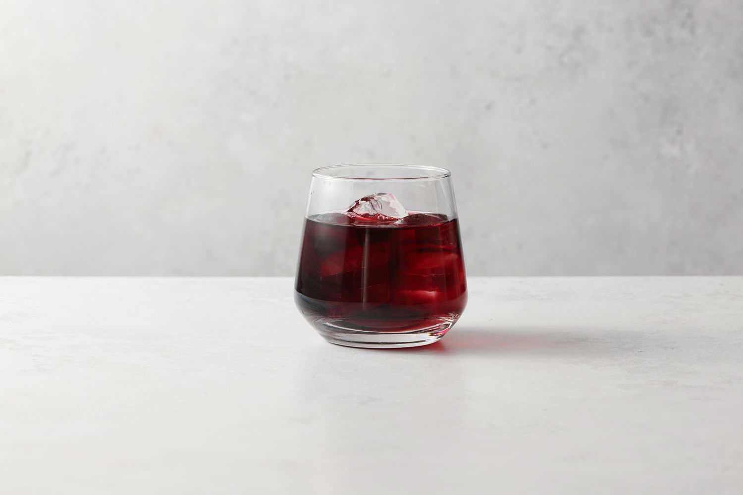 A glass of ice with red wine and orange bitters