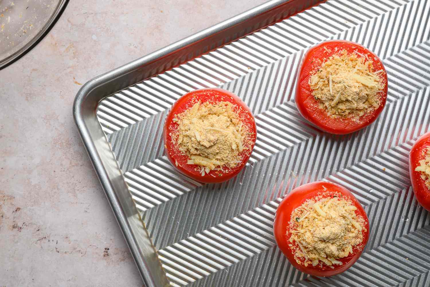 A baking sheet with four tomatoes filled with the breadcrumb-cheese filling