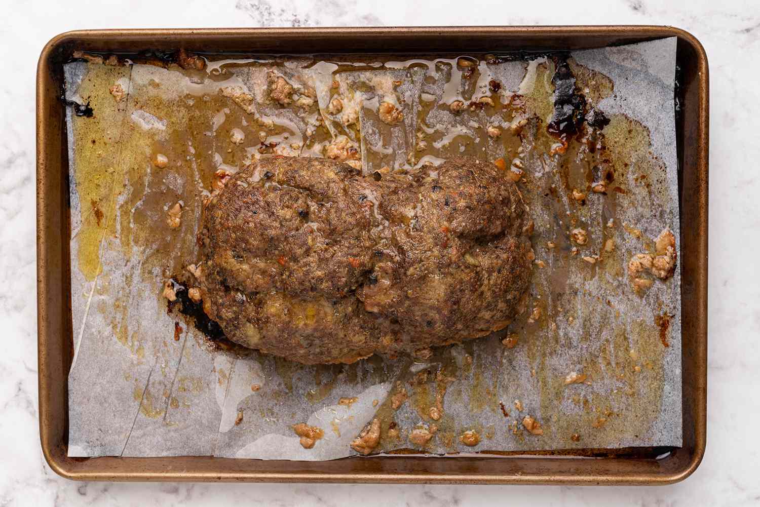 Baked meatloaf on a parchment paper lined baking sheet 