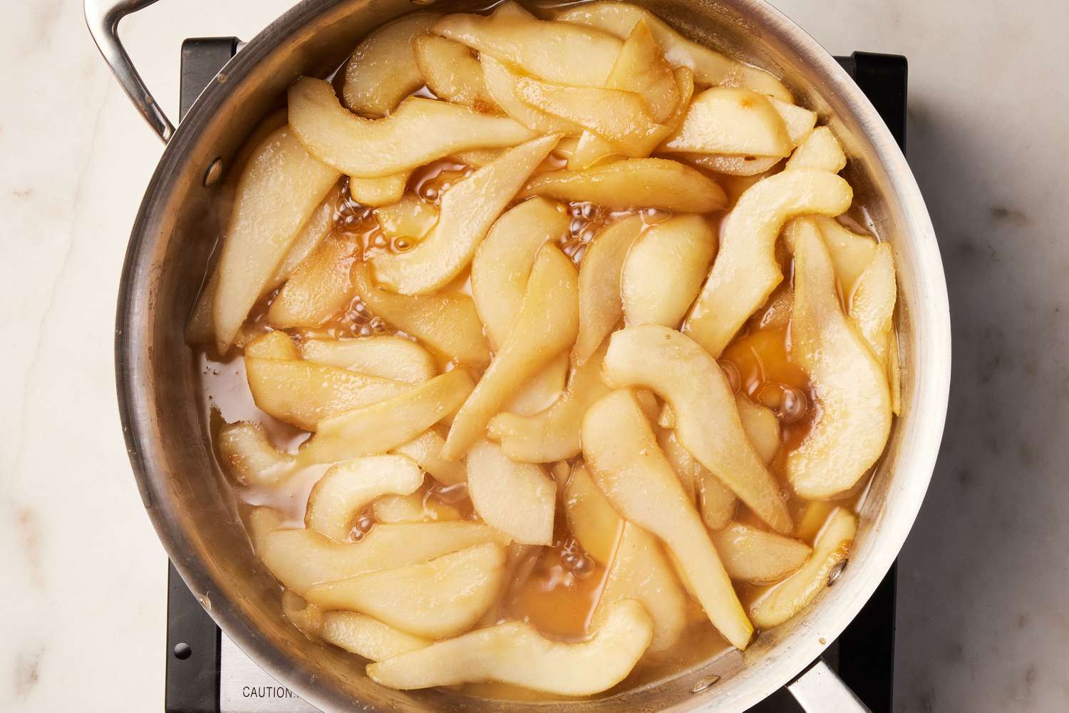 A large pot of sliced pears cooking down in butter, brown sugar, and vanilla