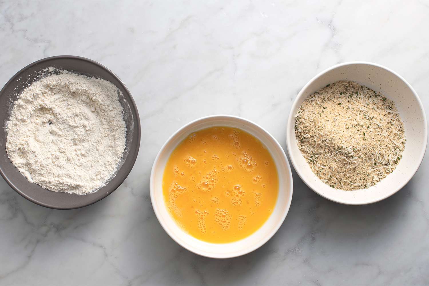 Bowls with egg mixture, flour and seasoned breadcrumbs
