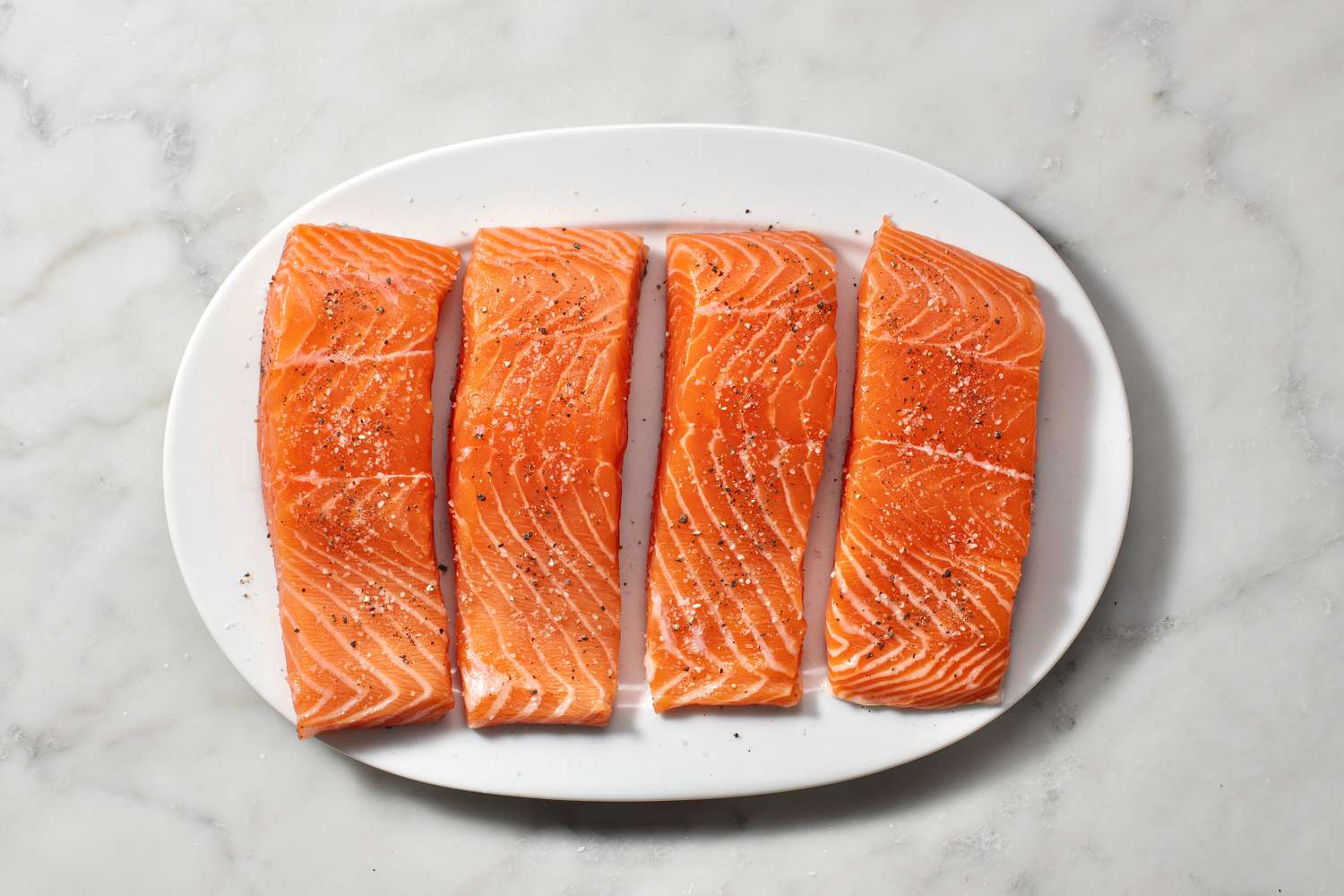 Pieces of salmon on a plate seasoned with salt and pepper