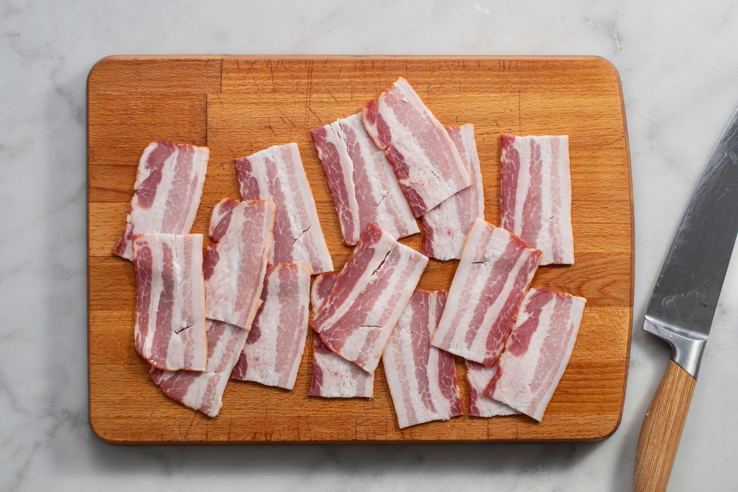 Pieces of bacon cut in half on a cutting board