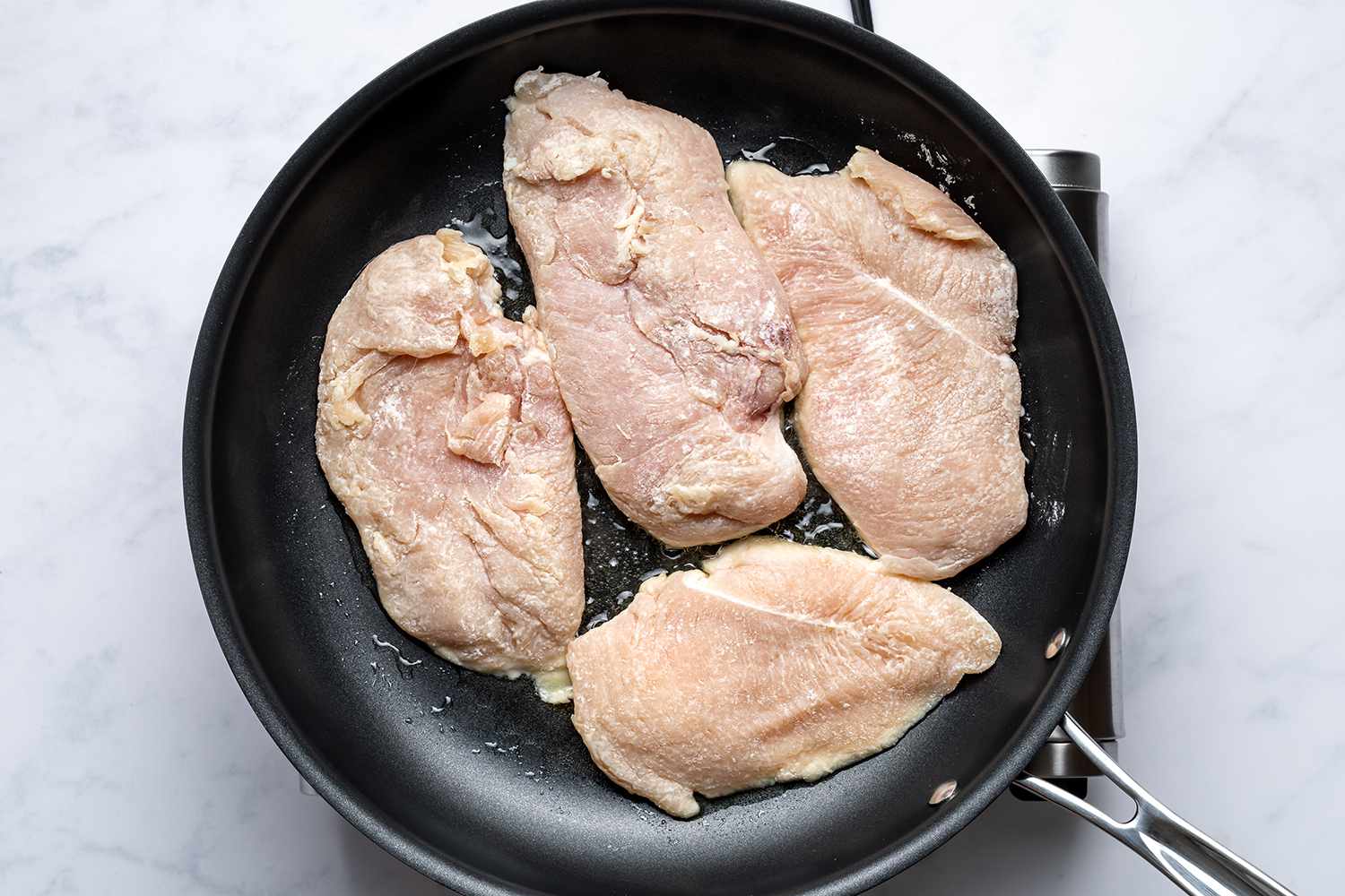 Chicken breasts fitting snugly in a large skillet in a single layer