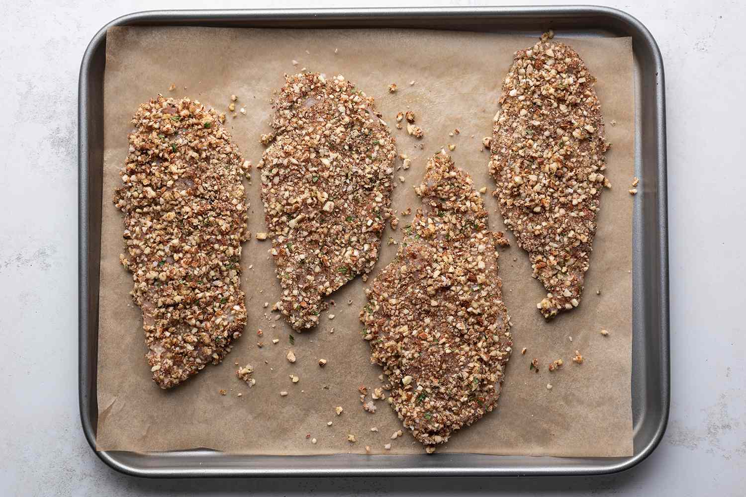 Almond crusted chicken on a parchment paper lined baking sheet 
