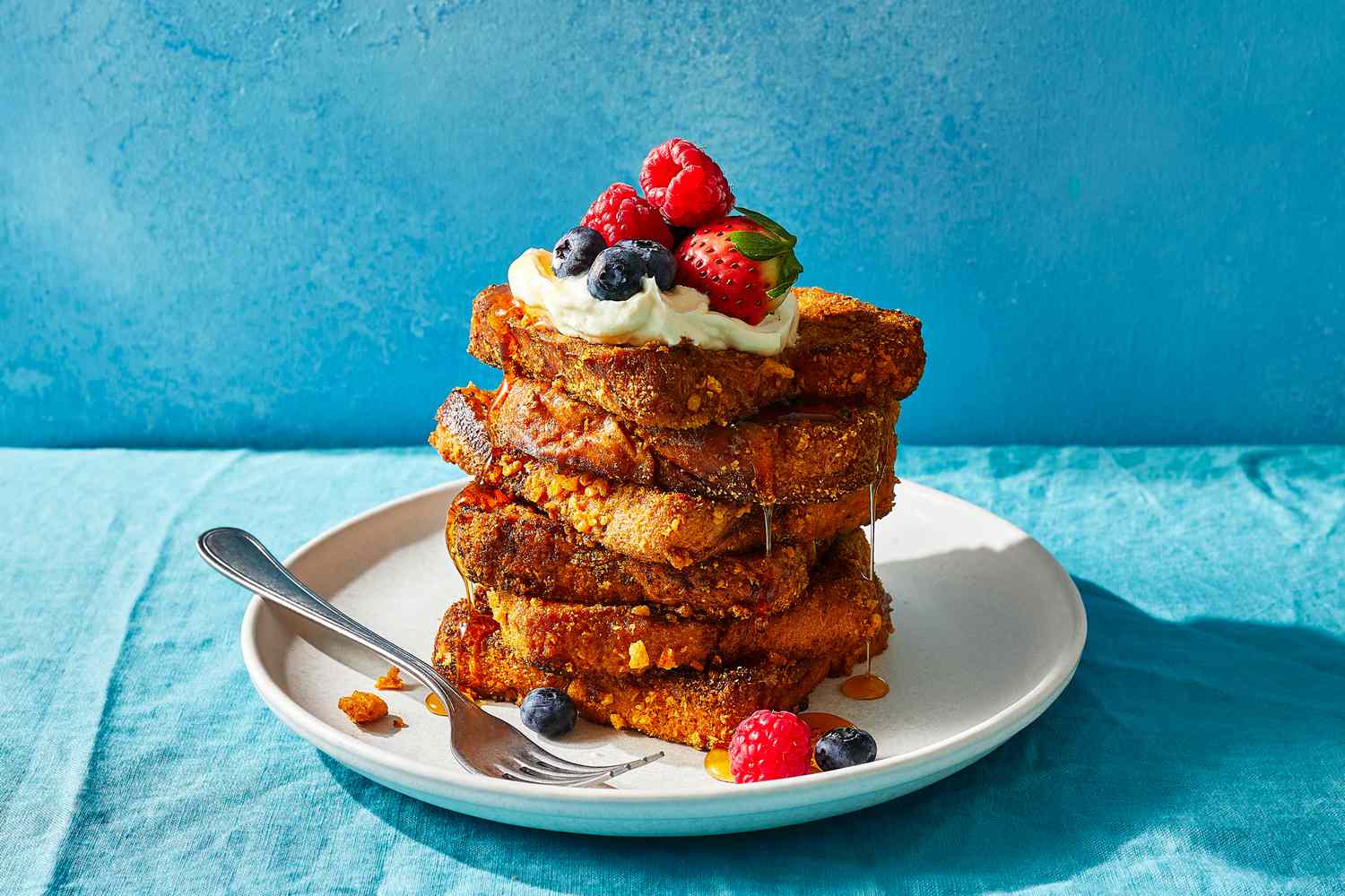 A stack of Cap'n Crunch French toast topped with whipped cream and berries