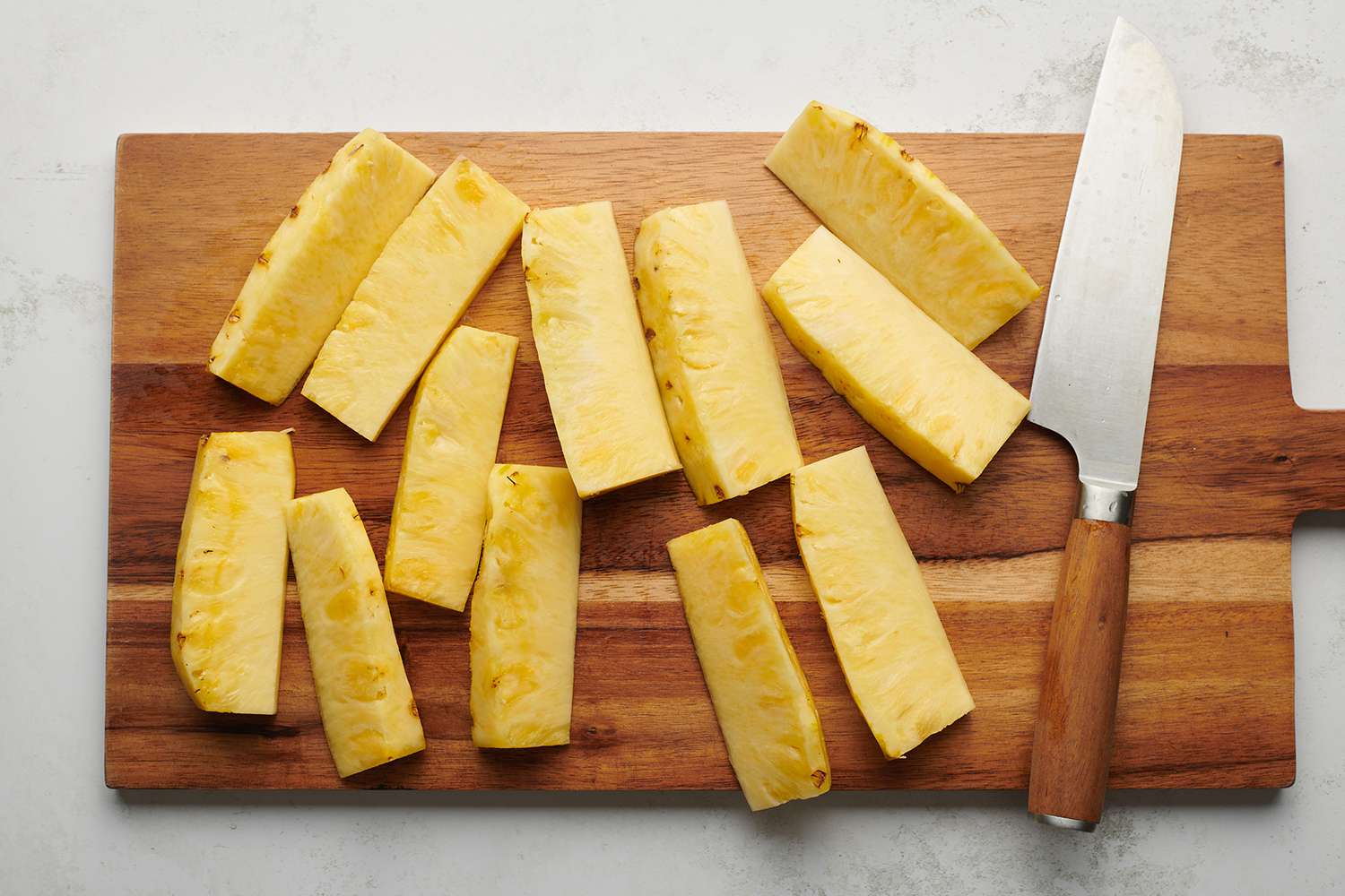 Sliced pineapple on a wooden cutting board with a knife 