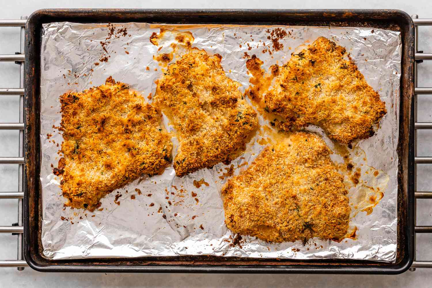 Panko-crusted oven-fried haddock fillets on a rimmed baking sheet lined with foil