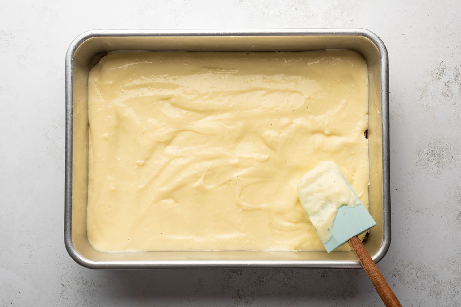 Baking dish with graham crackers and pudding mixture, and a spatula 