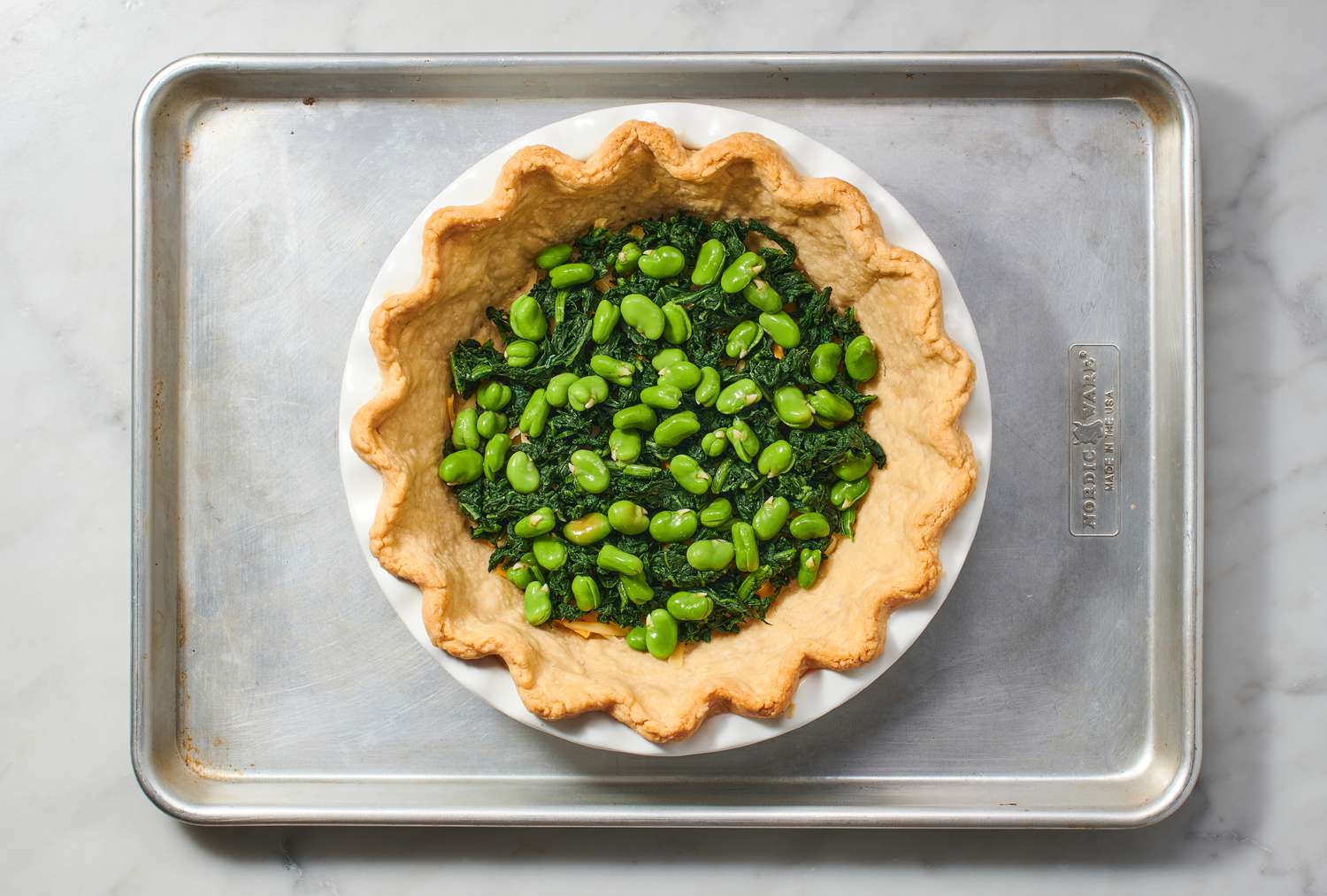 A par-baked pie crust layered with cheese, spinach, and fava beans