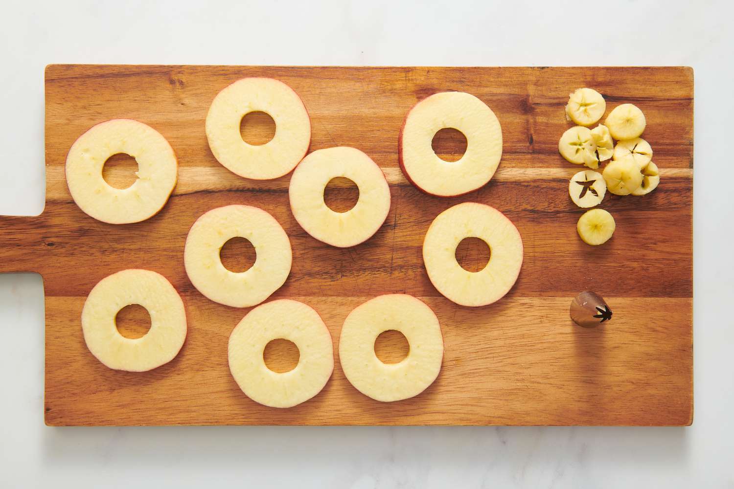 A cutting board with large, thin slices of apples with the core removed with a pipping tip