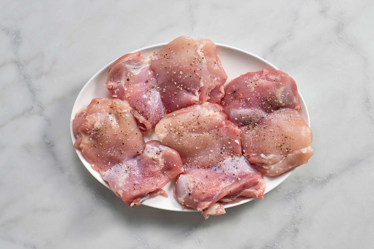 chicken pieces on plate seasoned with salt and pepper