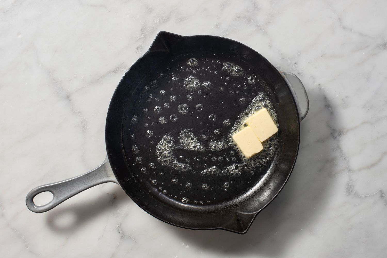 Pieces of butter melting in a hot cast iron pan