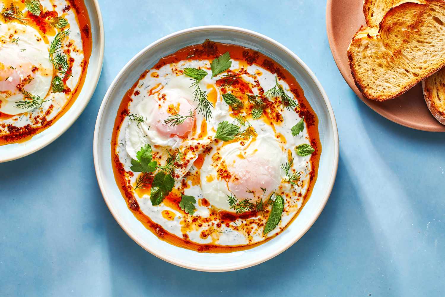 Poached eggs served with yogurt sauce, brown butter, and topped with herbs