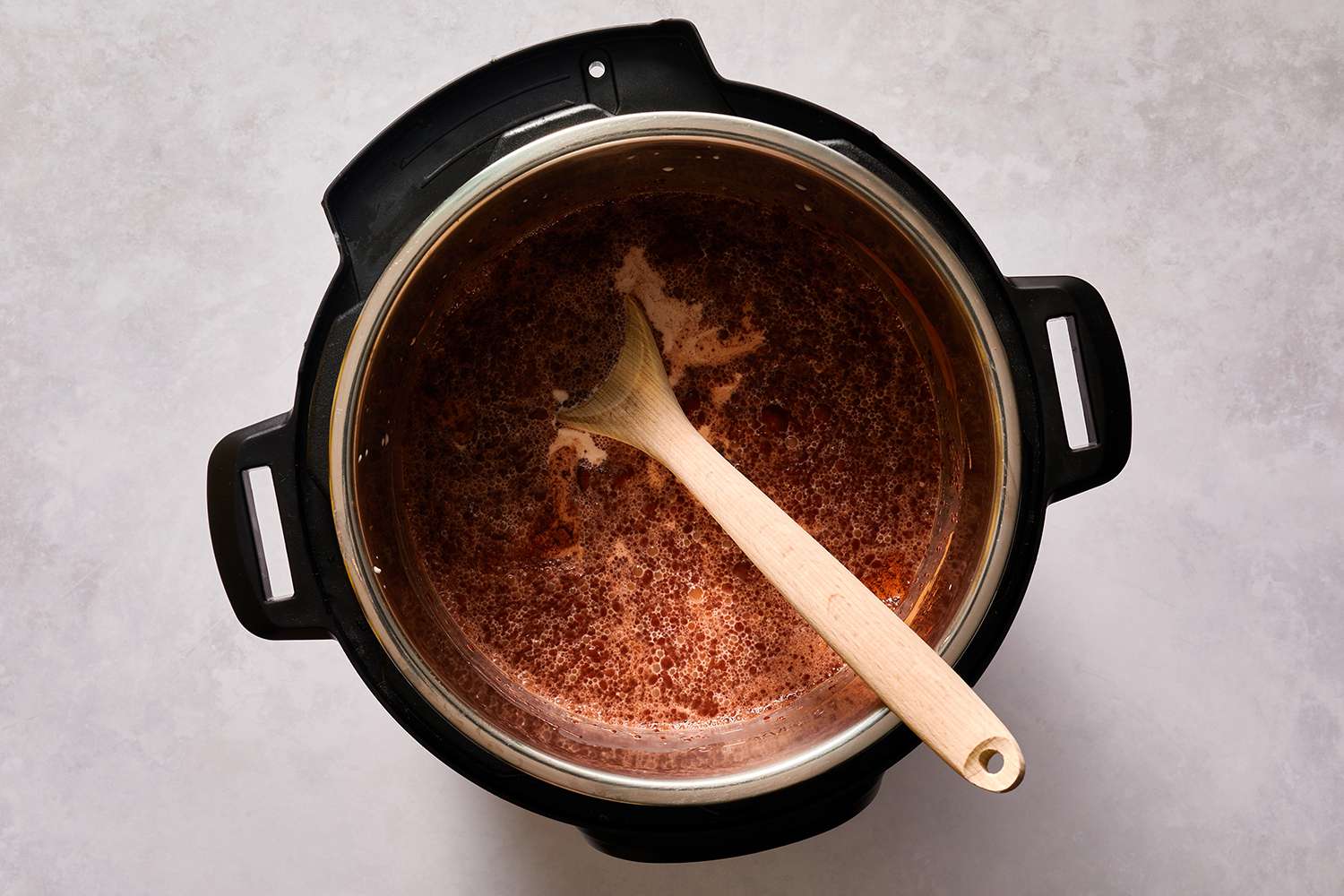 hot chocolate ingredients in crock pot with wooden spoon