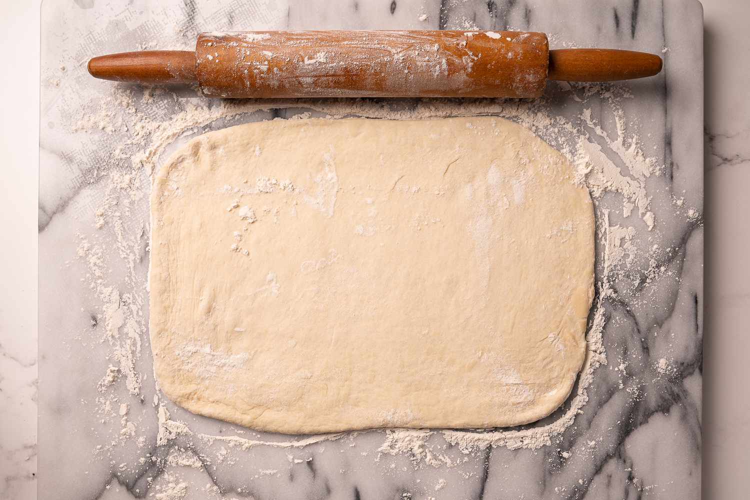 Bread dough rolled out into a rectangle on a floured surface