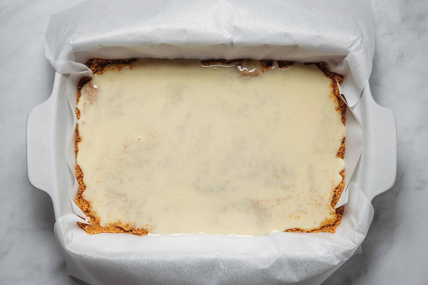 Graham cracker mixture with sweetened condensed milk on top in a prepared baking dish