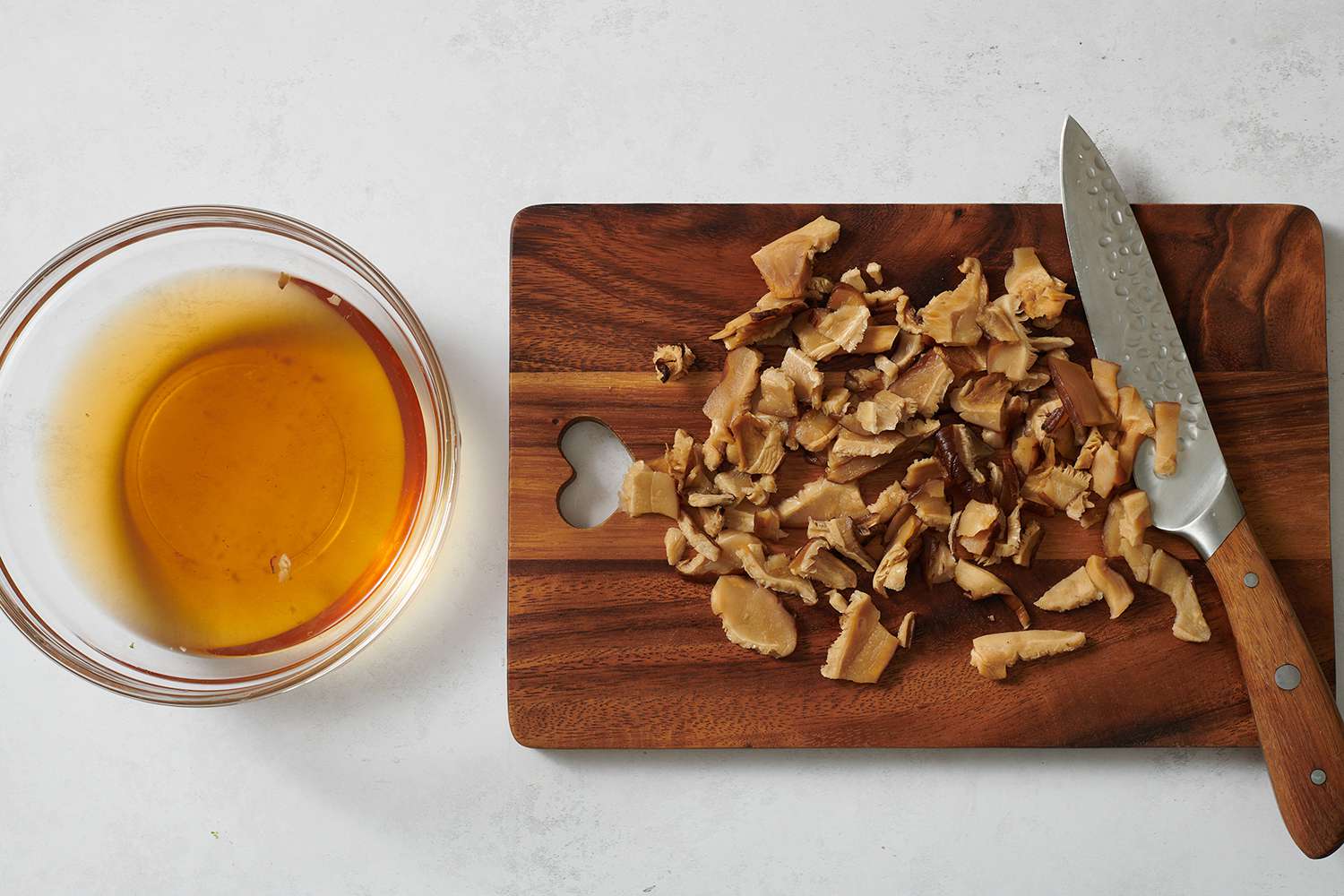 Sliced mushrooms on a cutting board with a small bowl of mushroom water