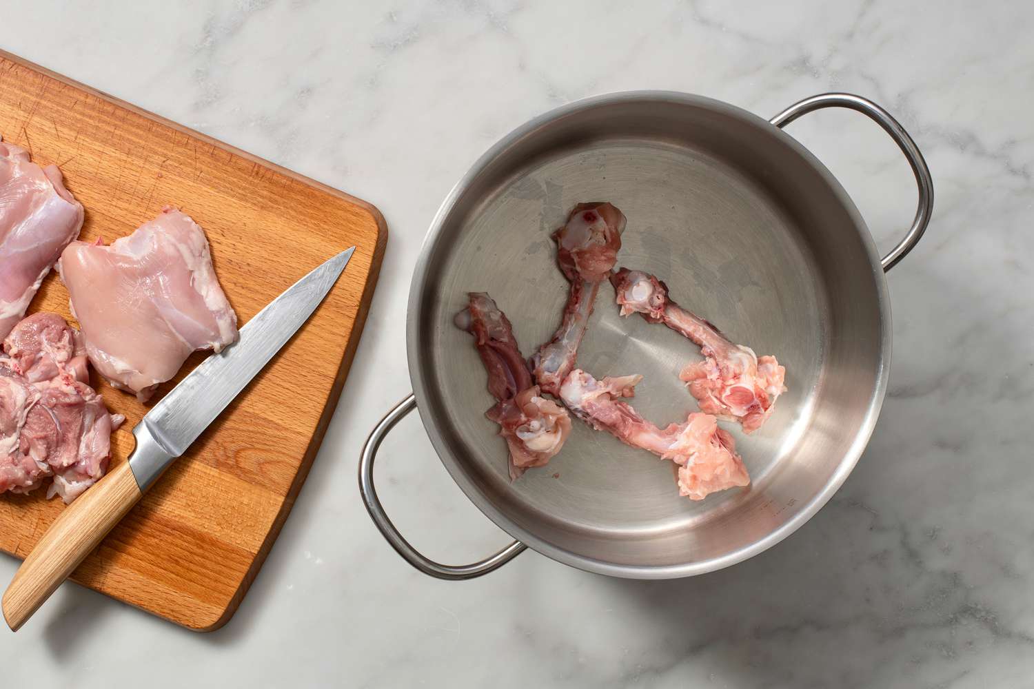 chicken bones in large pot with meat on cutting board