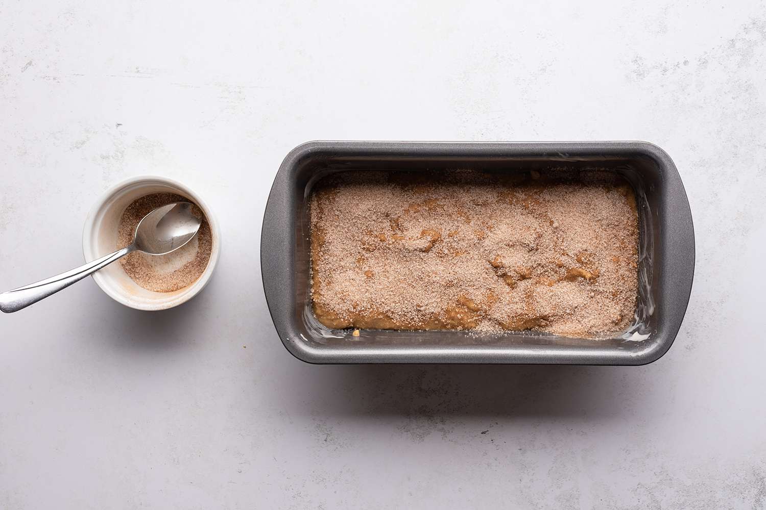 Cinnamon sugar in a bowl and on top of the batter in a loaf pan 