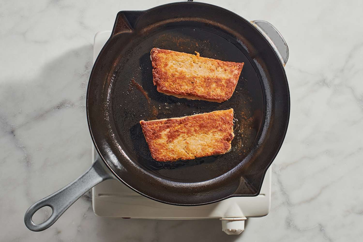 scrapple frying in a cast iron skillet