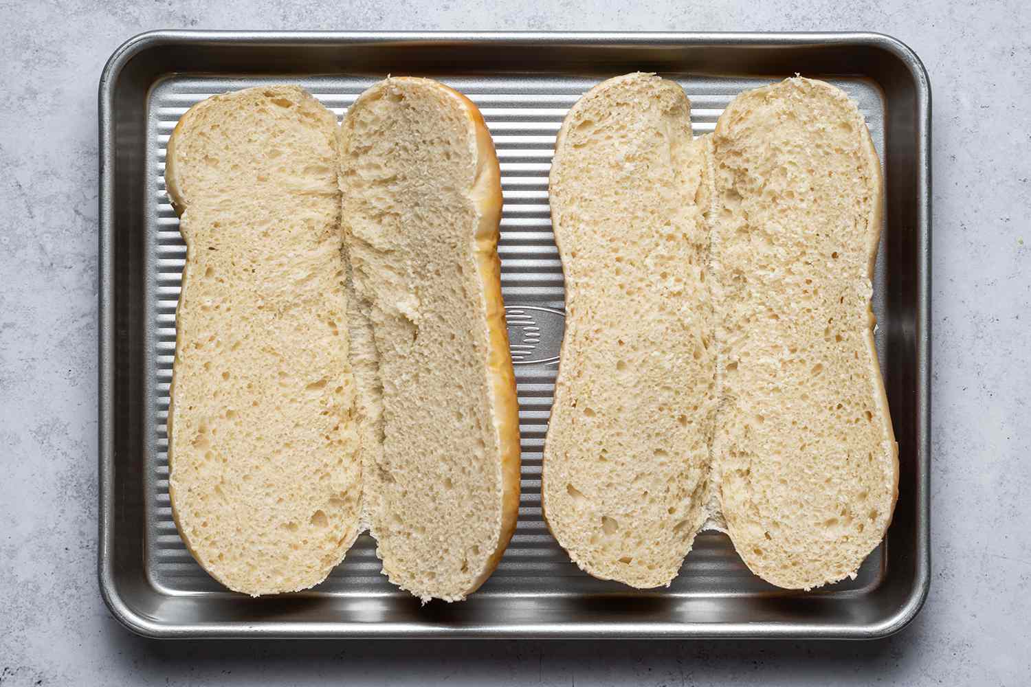 Two sliced rolls on a baking sheet