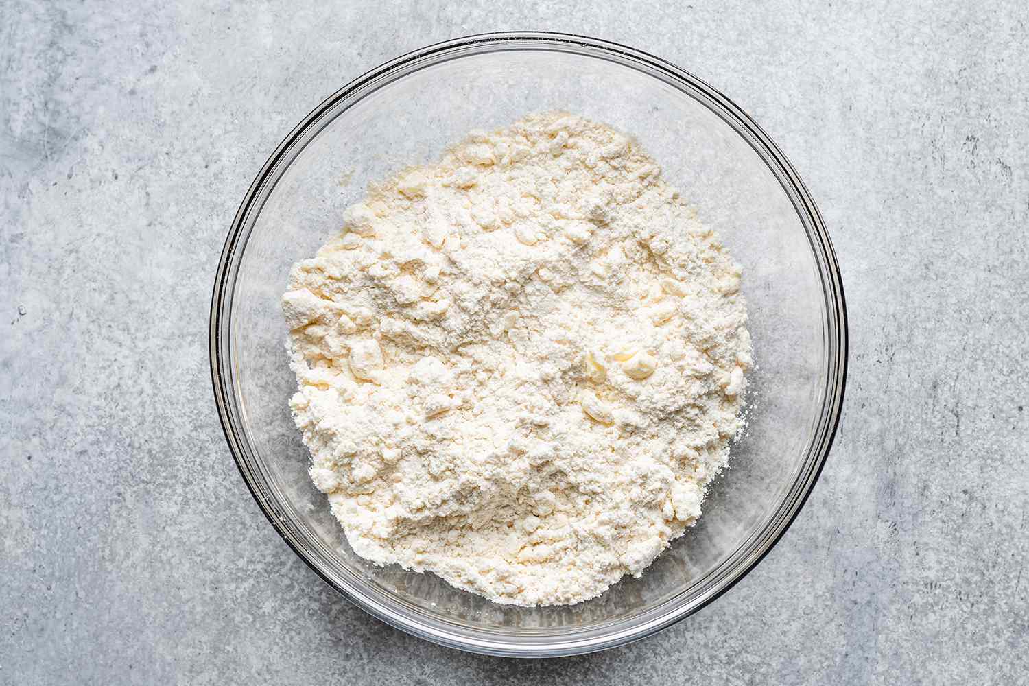 flour with small pieces of butter in a glass bowl