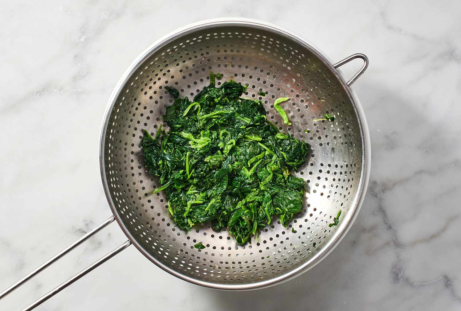 A strainer with rinsed spinach