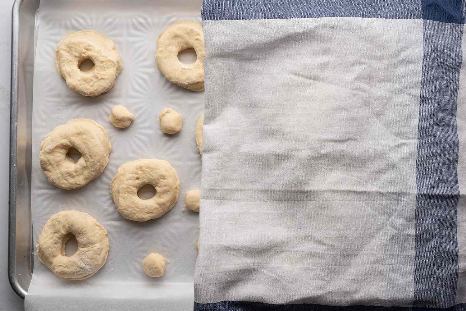 Doughnut dough on a baking sheet, covered with a towel 