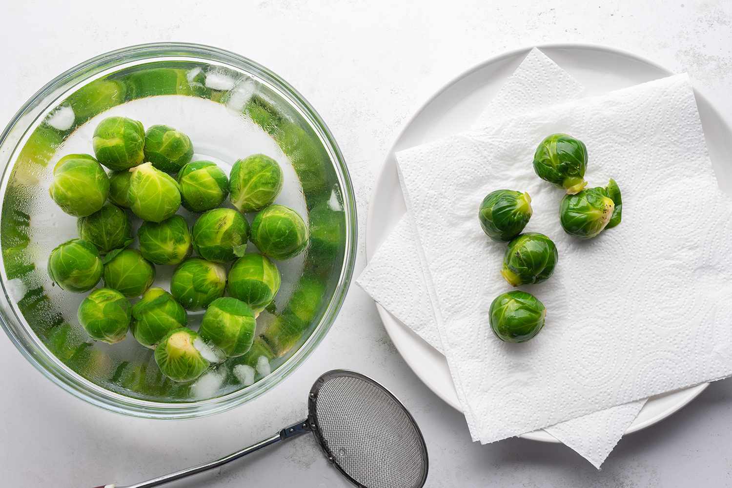 Brussels sprouts in a bowl with water, and on a paper towel lined plate 