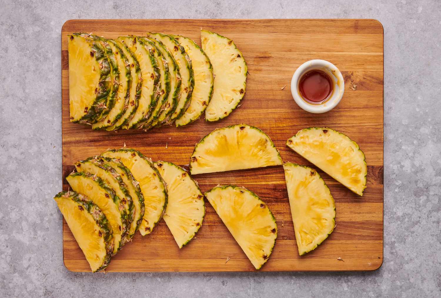 A cutting board with half moon slices of pineapple brushed with honey