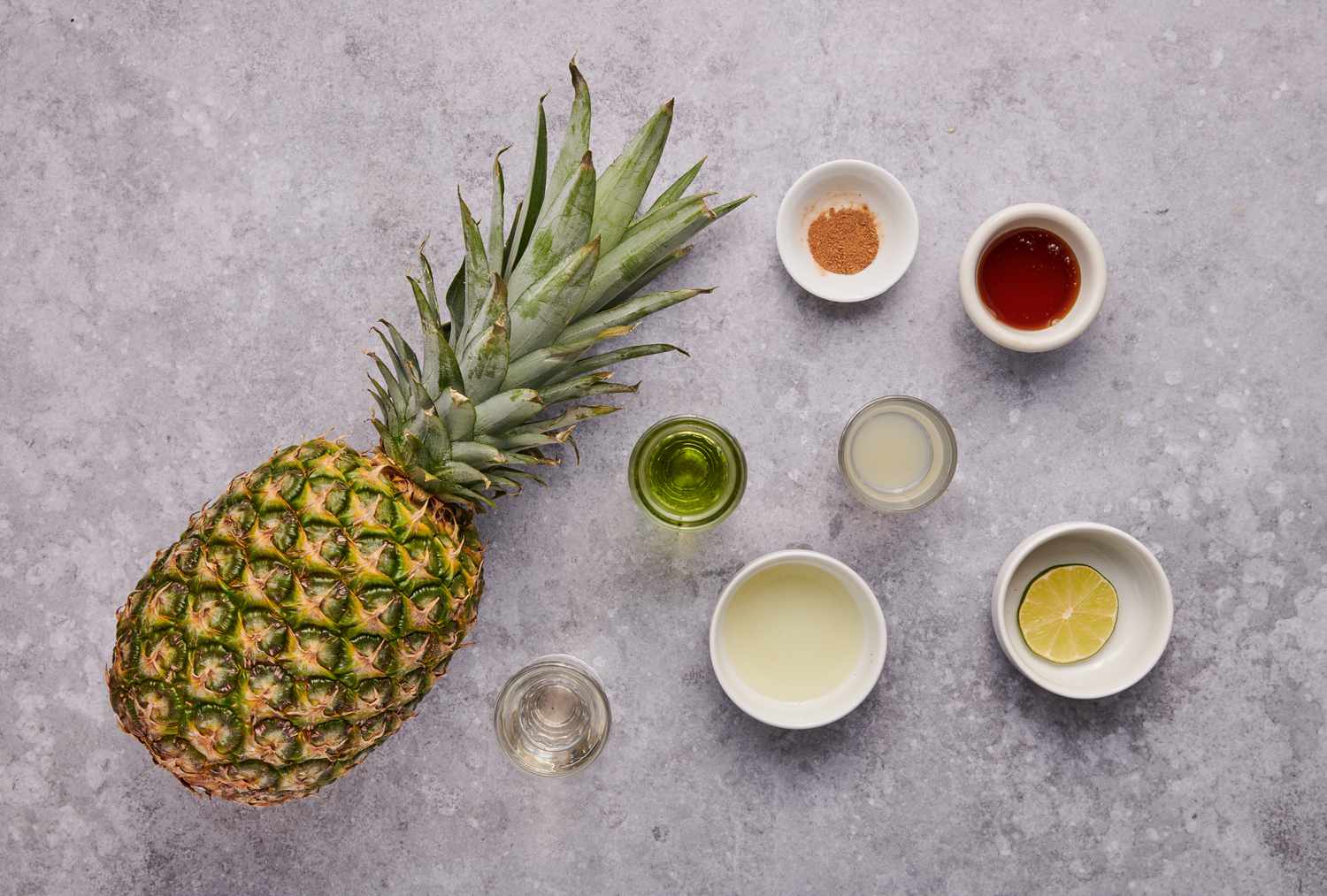 Ingredients to make a grilled pineapple chartreuse swizzle cocktail