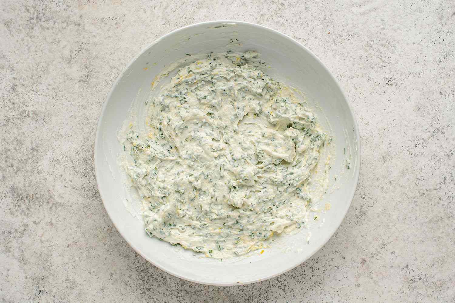 Lemon zest, sour cream, chives, dill, and onion powder in a bowl 