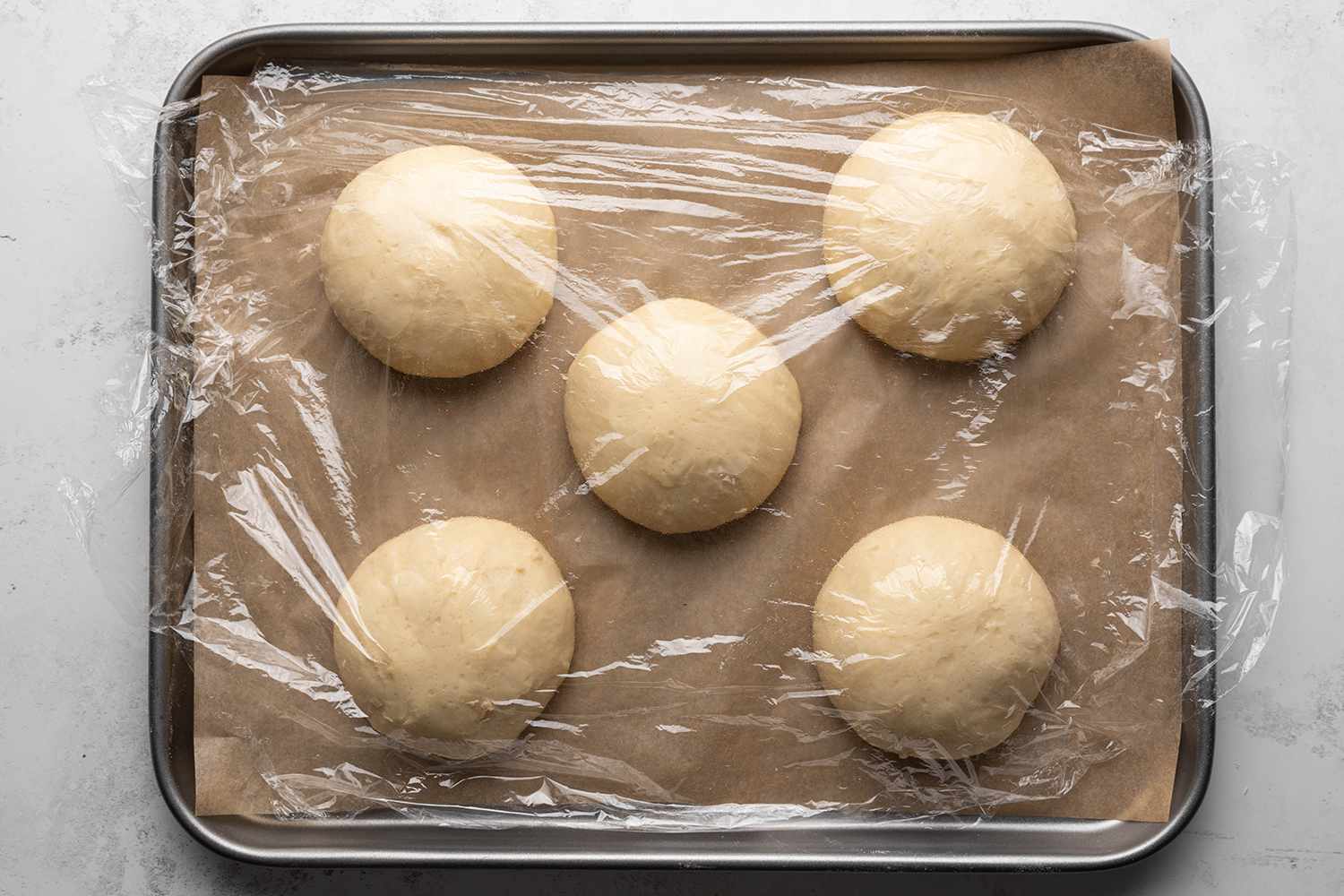 Risen dough covered in plastic wrap