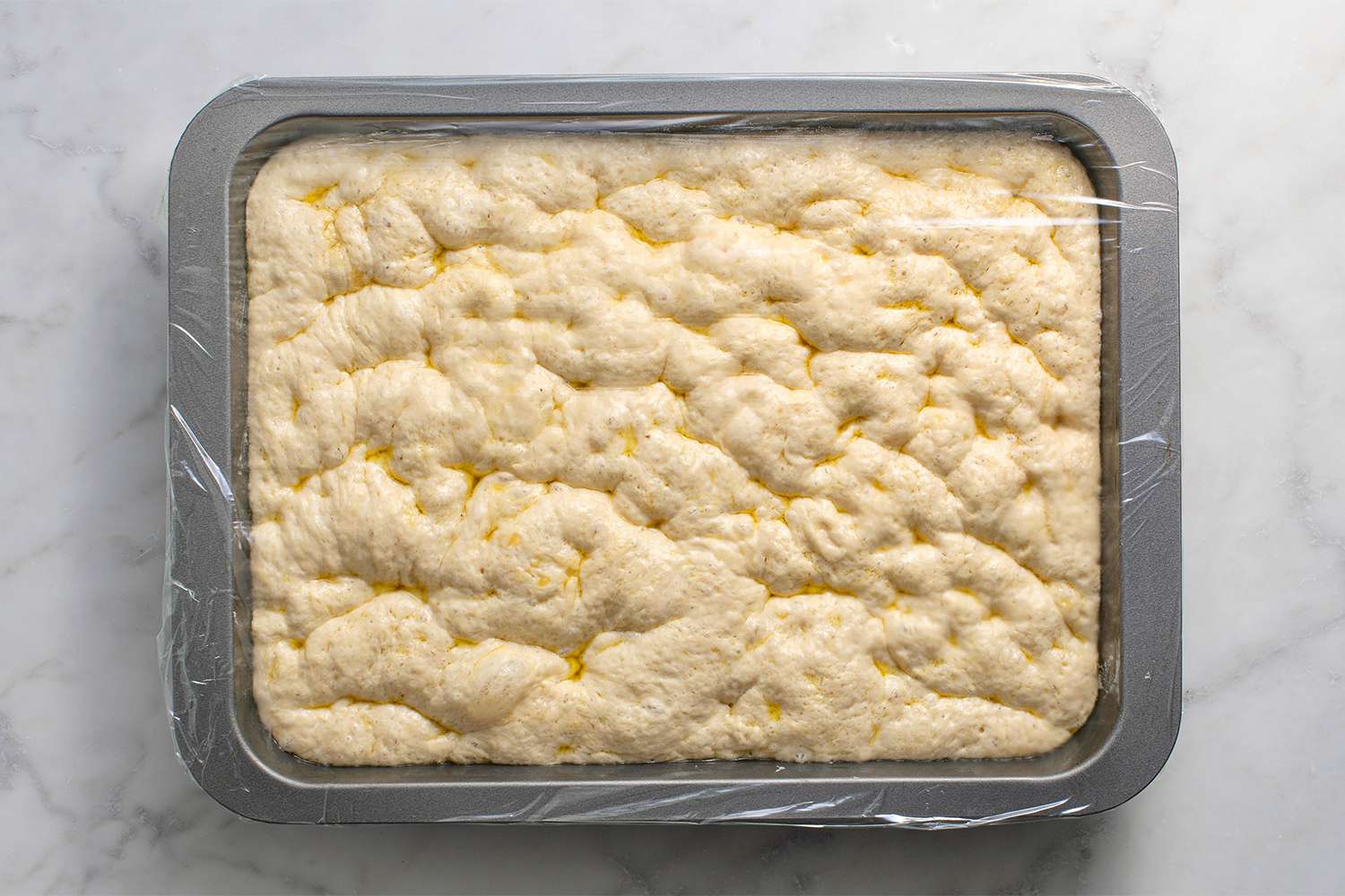 Dough in an oiled baking dish, covered with plastic wrap 