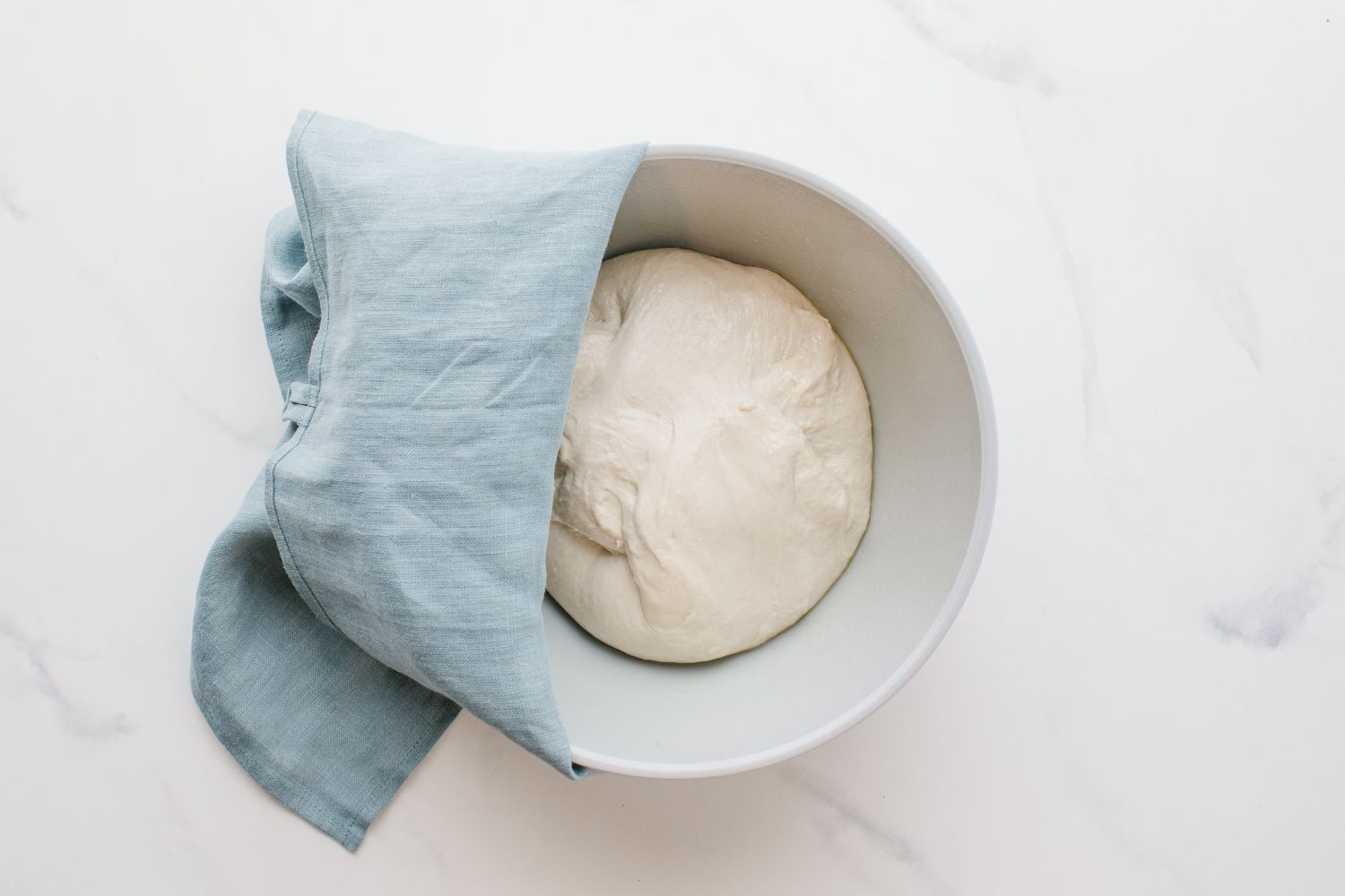 Dough in a bowl covered with a towel