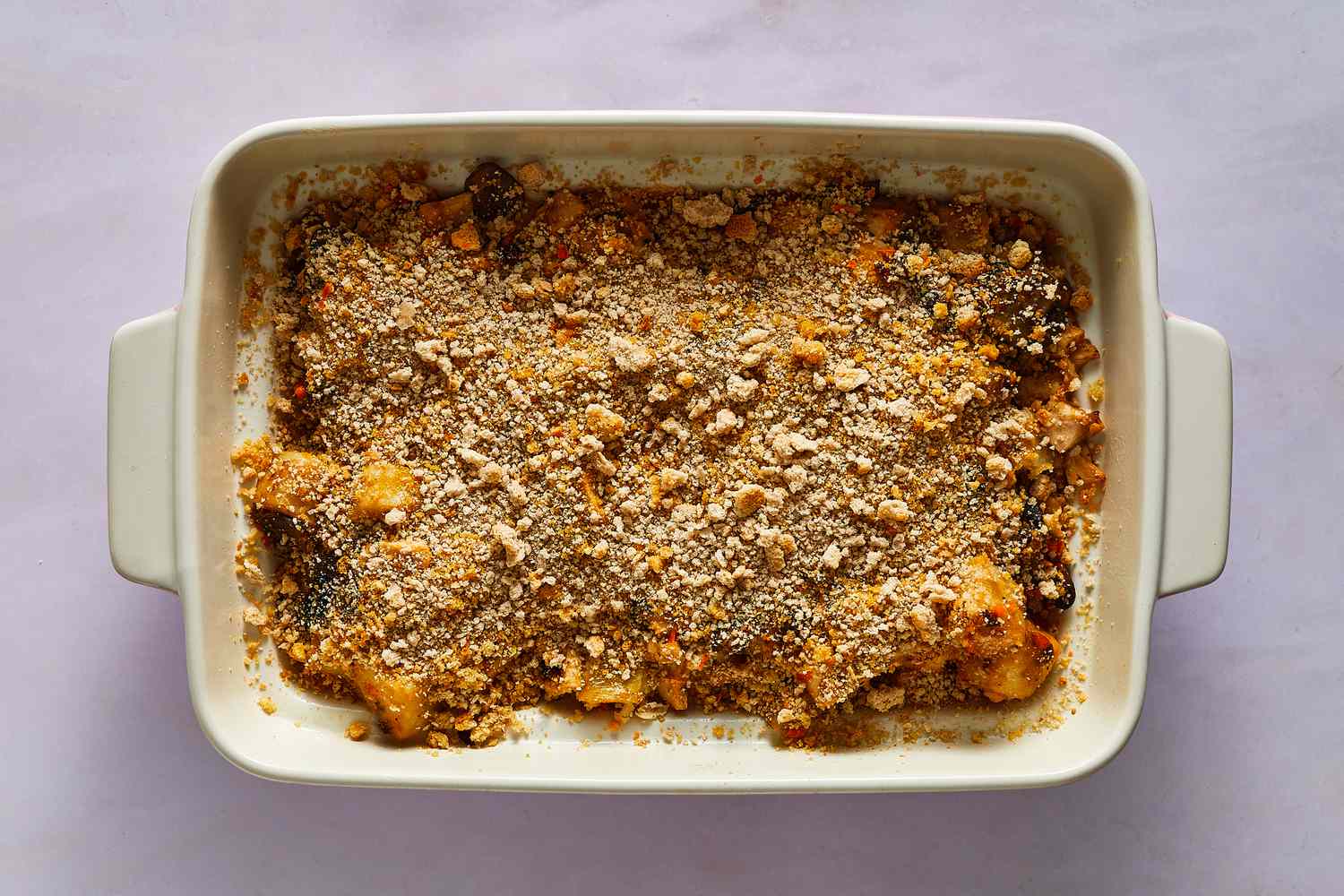 A baking dish of potatoes, chicken, and creamy mushrooms topped with buttered breadcrumbs