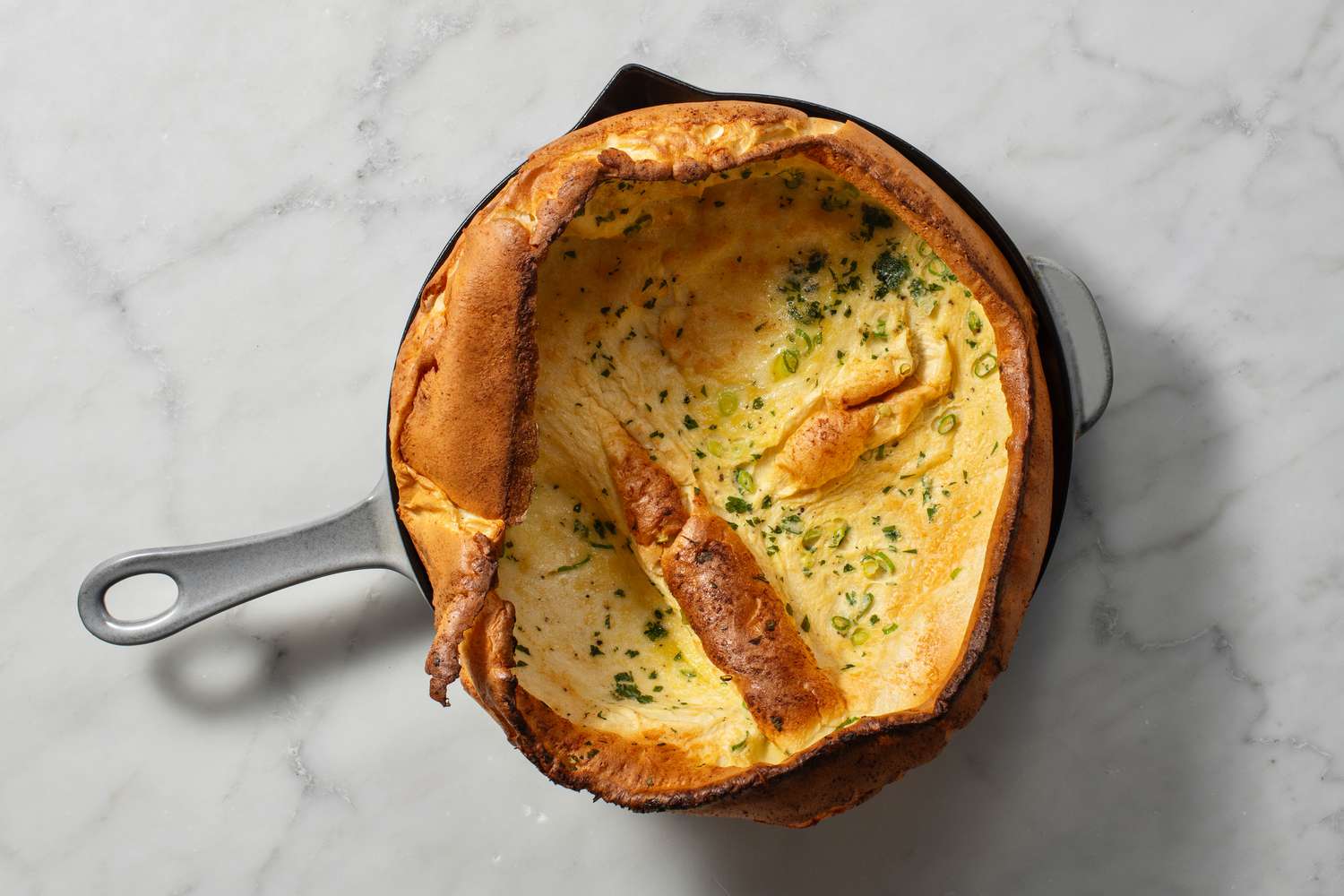 A cooked Dutch Baby in a cast iron pan