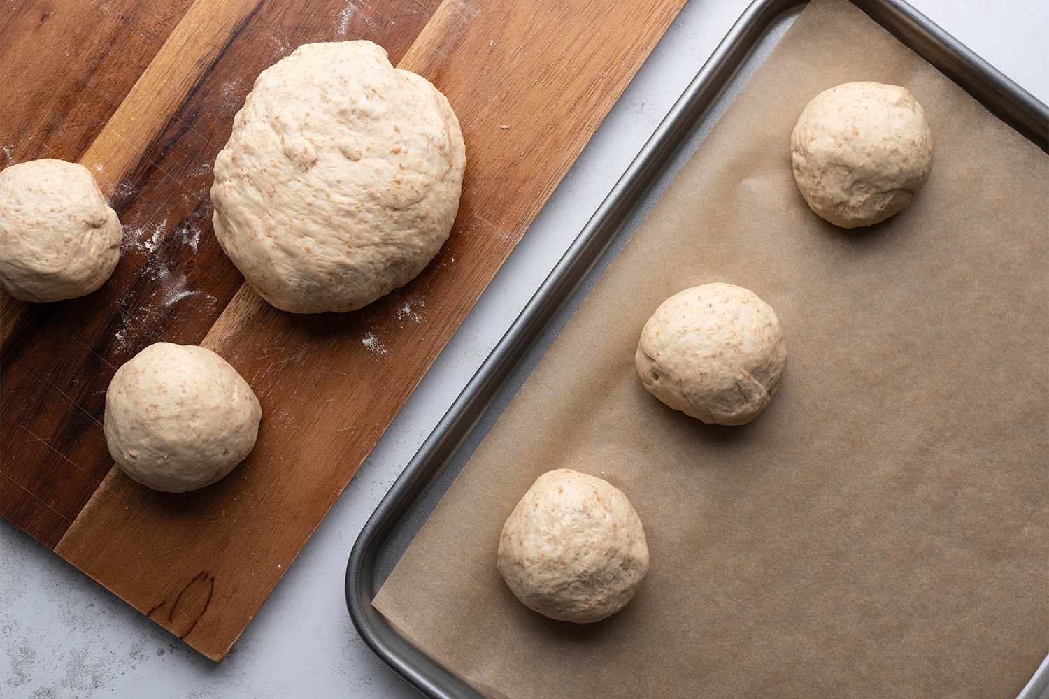 Dough balls on a wooden board and on parchment paper lined baking sheet 