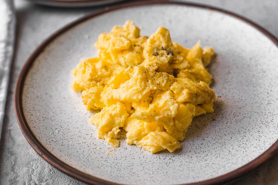 A plate of fluffy, scrambled eggs topped with salt and pepper