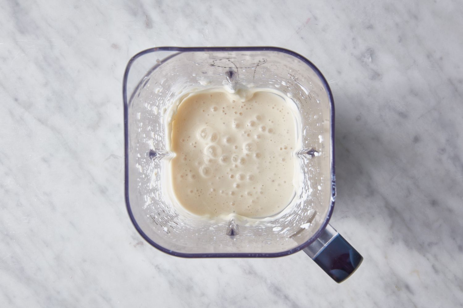 The pitcher of a blender with a pureed banana smoothie