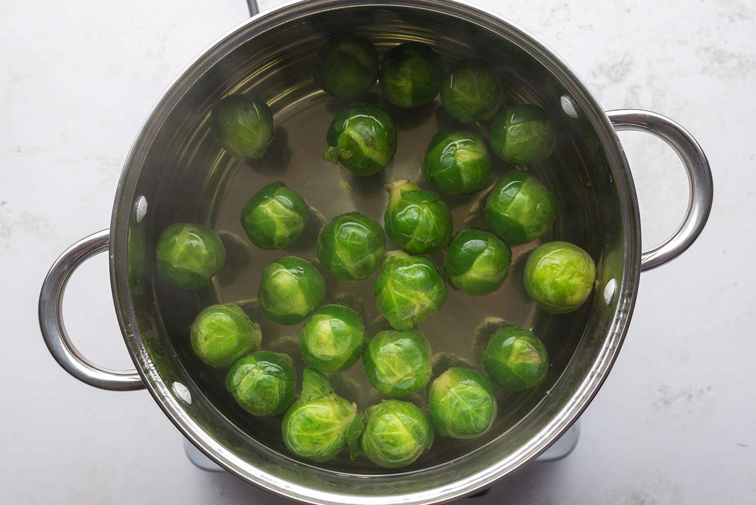 Brussels sprouts in a pot with water, on a burner