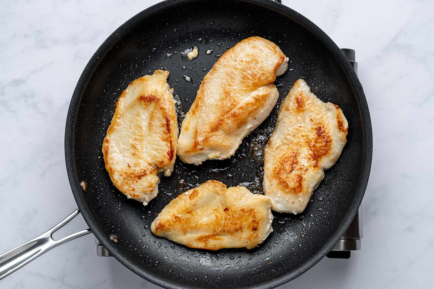 Lightly browned chicken breasts in a skillet
