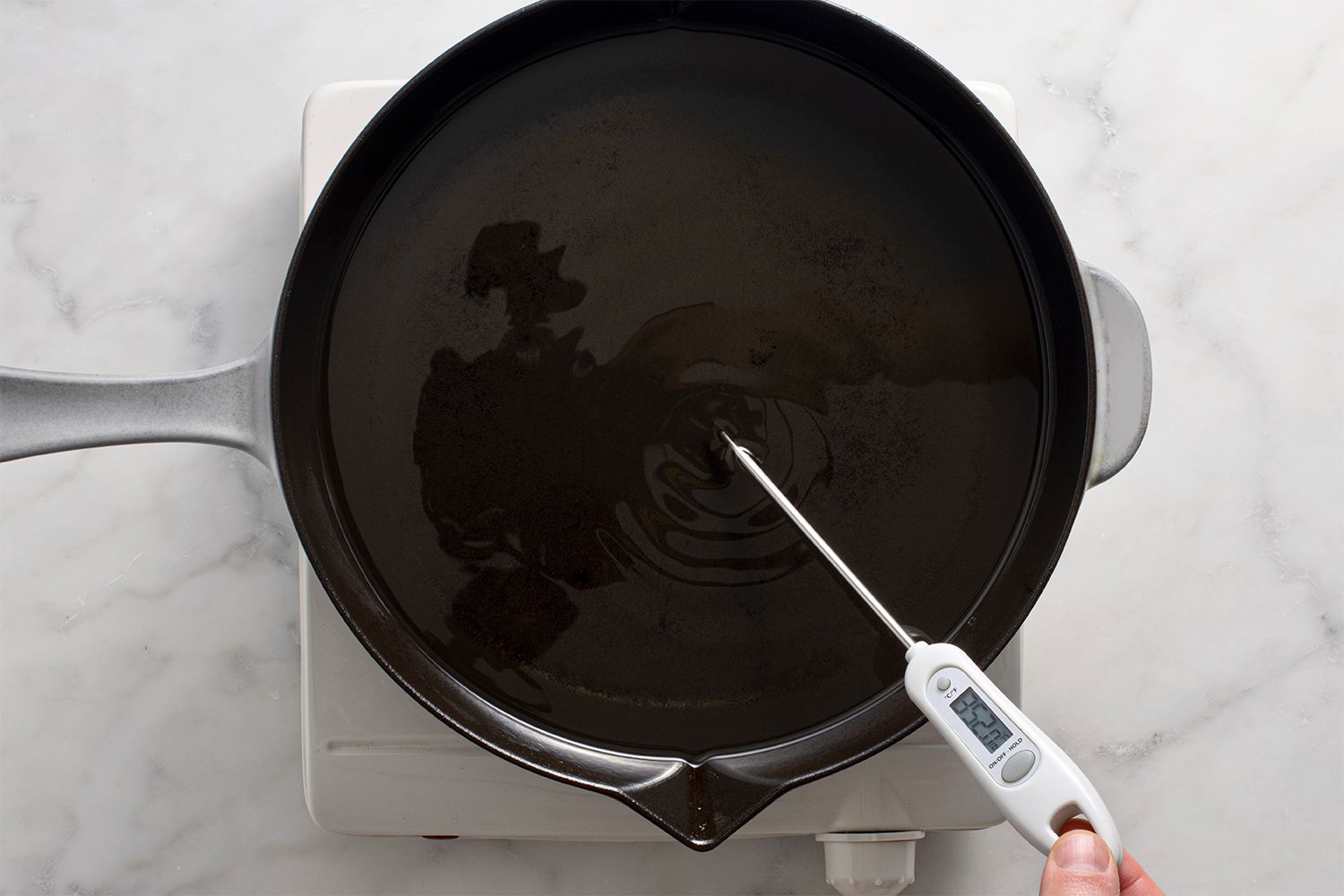 Oil in a pan on a burner, with a thermometer 