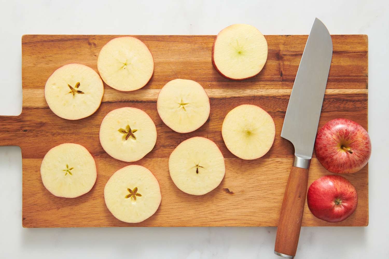 A cutting board with large, thin round slices of apples
